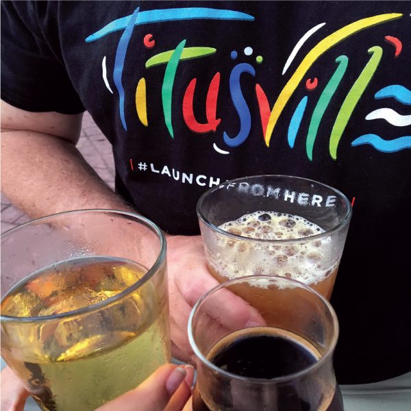 Person drinking beer wearing Titusville shirt