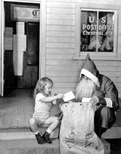 A little girl helps Santa at the Christmas, Florida Post Office