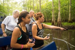 People on Airboat pointing and looking at wildlife in water