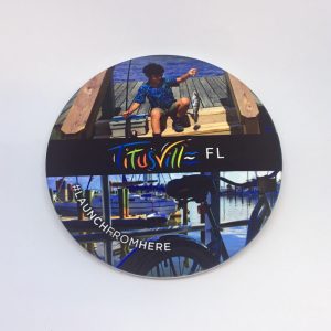 Launch From Here coaster featuring a kid holding a fish and a bike at the marina
